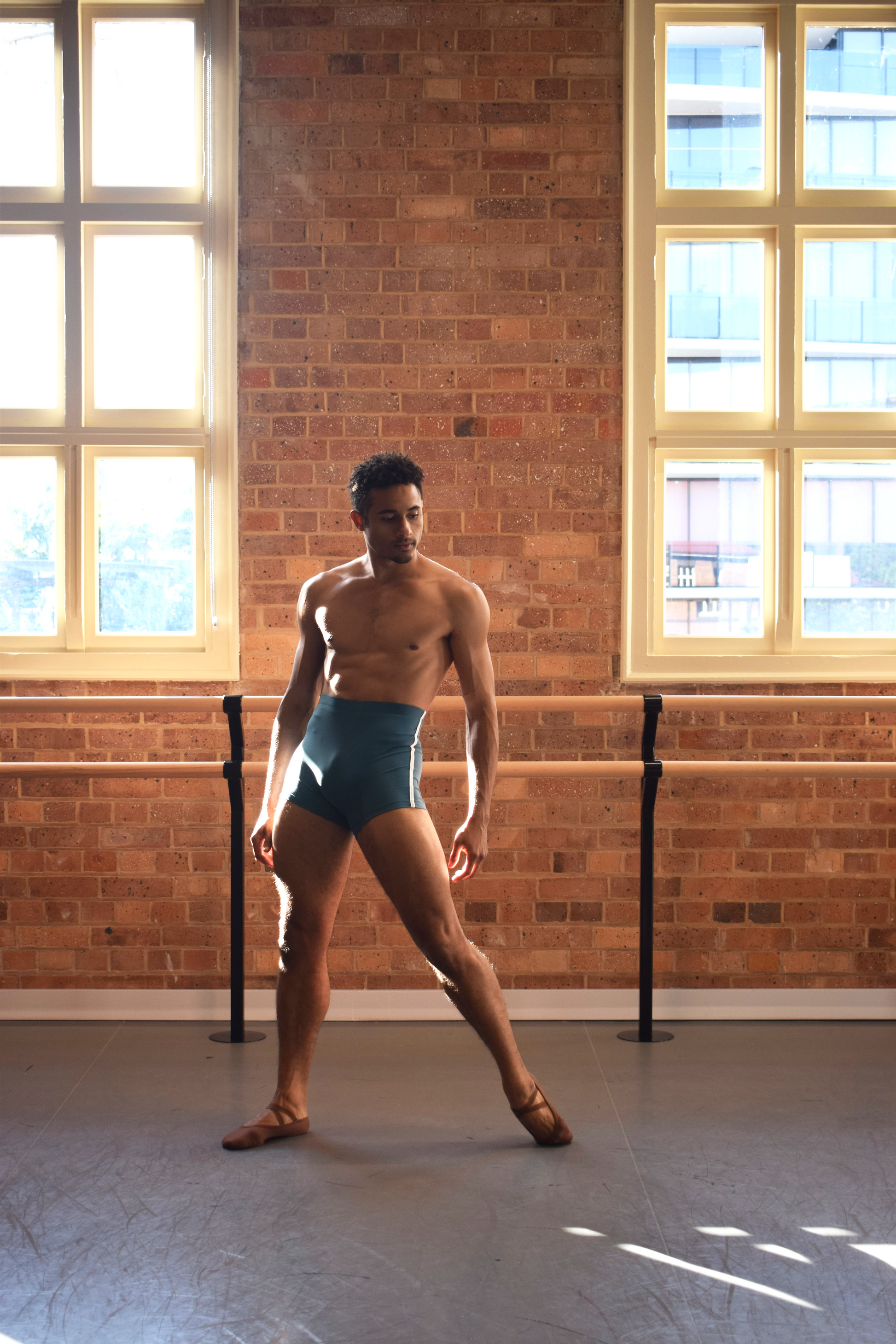 Male dancer, Patricio Reve wearing Gents 1/4 GT 1.0 short tights in Coastal Blue with white piping – mid-thigh performance compression shorts