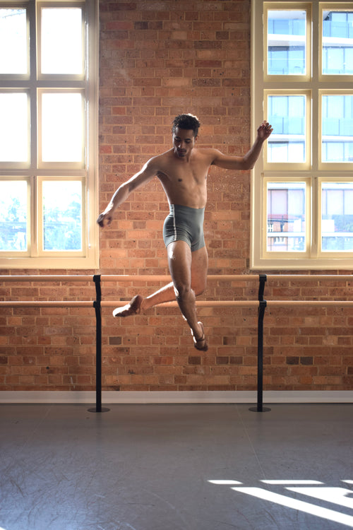 Male dancer, Patricio Reve wearing Gents 1/4 GT 1.0 short tights in Moss Green with white piping – mid-thigh performance compression shorts