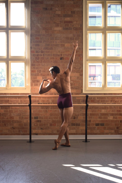Male dancer, Patricio Reve wearing Gents 1/4 GT 1.0 short tights in red with white piping – mid-thigh performance compression shorts